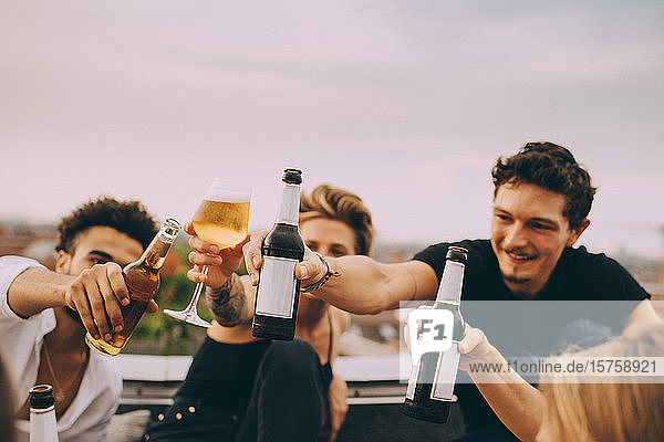 Freunde feiern mit Bier  während sie auf dem Dach der Stadt feiern