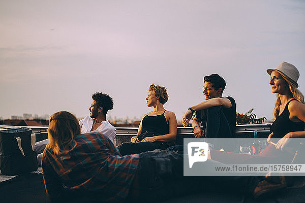 Freunde schauen weg und entspannen sich gemeinsam bei einer Dachparty gegen den Himmel in der Stadt