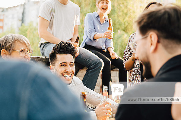 Lachende Freunde und Freundinnen beim Bierhalten auf Gartenparty