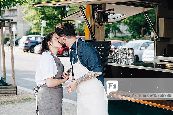 Männliche und weibliche Unternehmer küssen sich  während sie an einem Speisewagen stehen