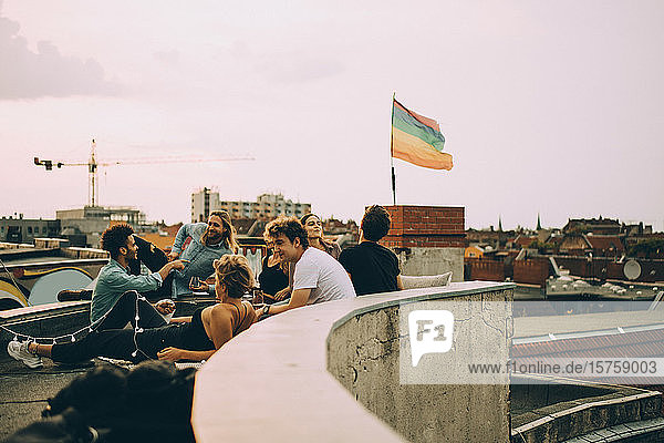 Freunde genießen Dachfeier in Stadt gegen Himmel