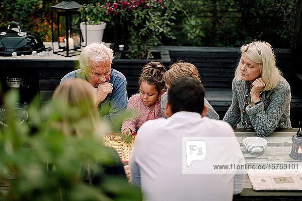 Mehrgenerationen-Familie spielt Brettspiel am Tisch  während sie auf der Terrasse sitzt