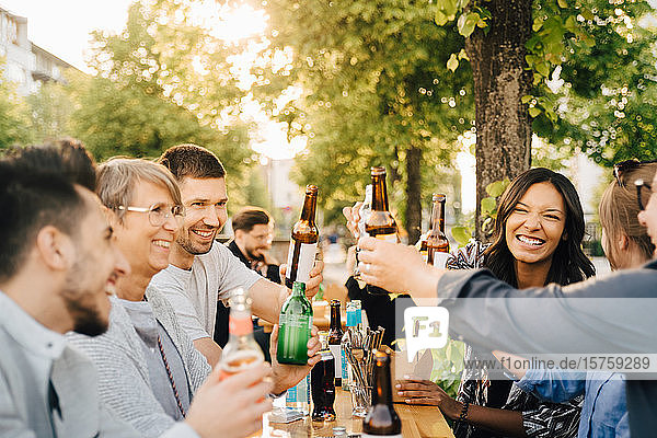 Male and female friends laughing while toasting with drinks at social gathering