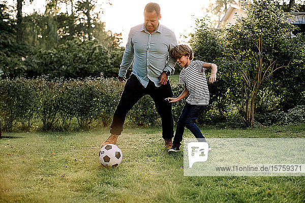 Volle Länge von Vater und Sohn beim Fußballspielen im Hinterhof während der Wochenendaktivitäten