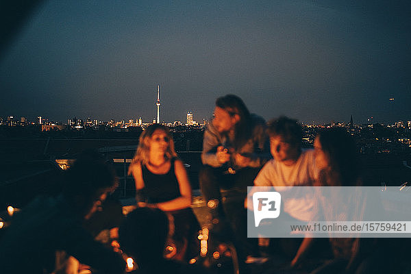 Freunde genießen in der Dämmerung auf der Terrasse gegen das Stadtbild
