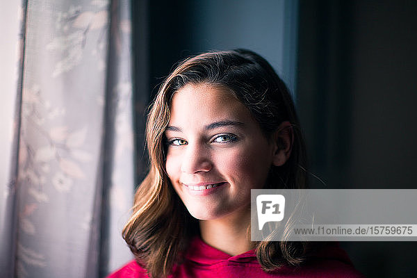 Young girl smiling by window at home