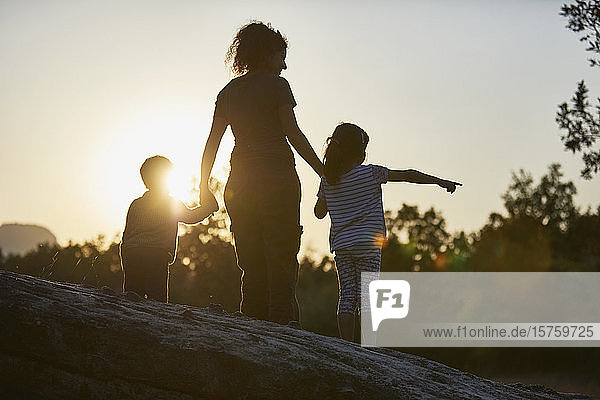 Mutter und Kinder erkunden die Natur bei Sonnenuntergang