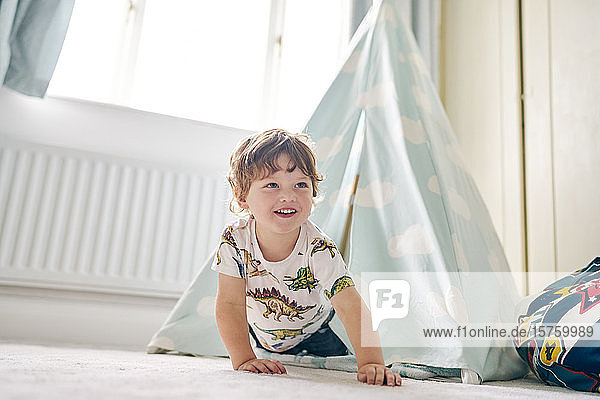 Toddler playing in a teepee in his bedroom at home