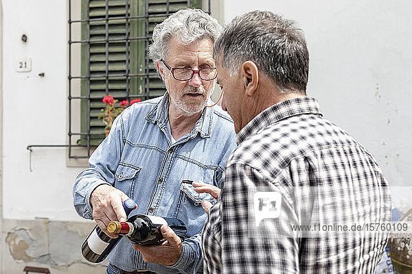 Men holding wine bottles in discussion  Florence  Italy