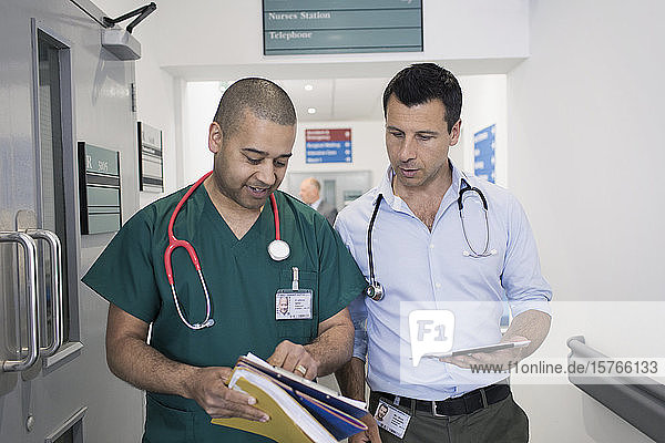 Männlicher Arzt und Chirurg besprechen Krankenakte  machen Visite im Krankenhauskorridor