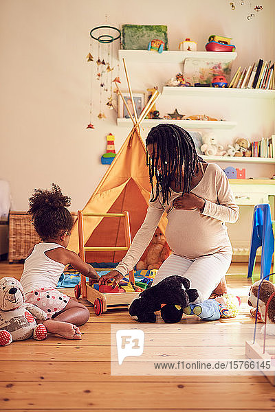 Schwangere Mutter und Kleinkind Tochter spielen mit Spielzeug