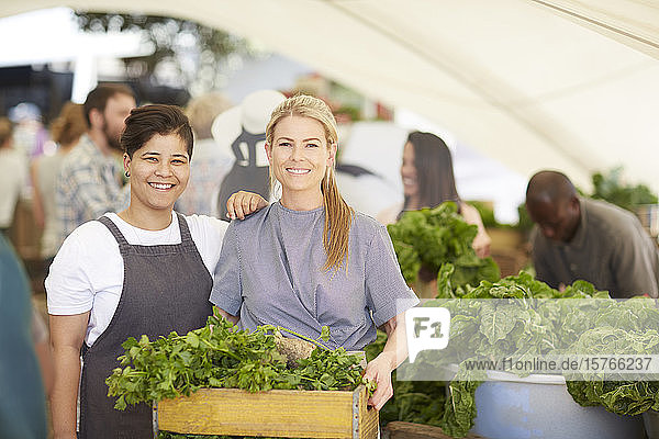 Portrait smiling women workers with crate of vegetables at farmerâ€™s market
