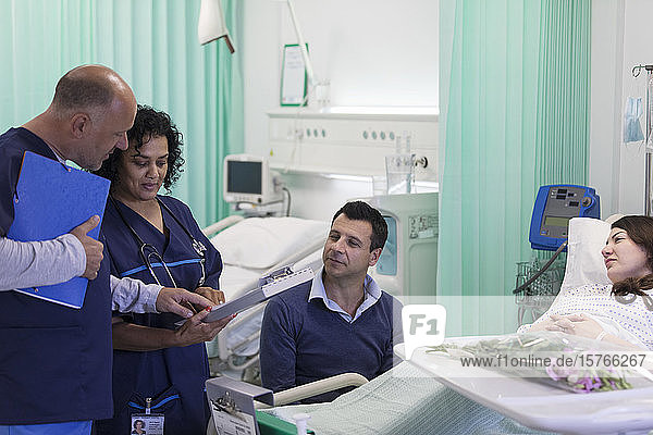 Ärzte mit Krankenblatt bei der Visite  Gespräch mit Ehepaar auf der Krankenstation