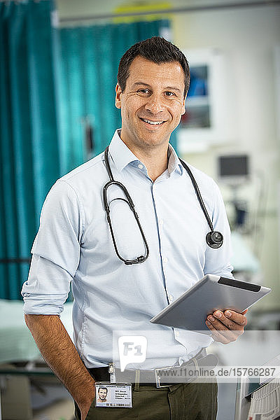 Portrait confident male doctor with digital tablet in hospital