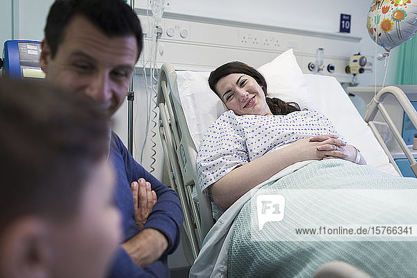 Lächelnder Patient bei einem Besuch mit seiner Familie im Krankenhauszimmer