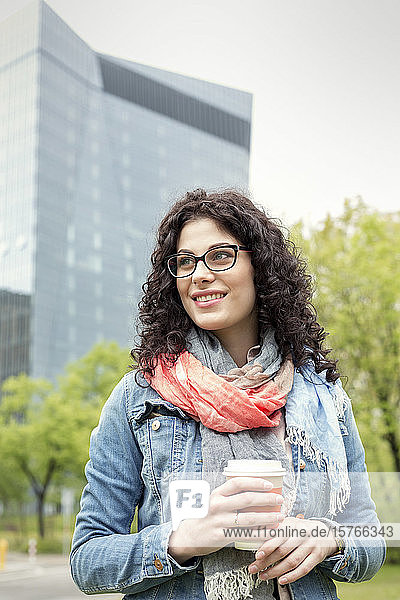 Lächelnde Frau trinkt Kaffee im Stadtpark