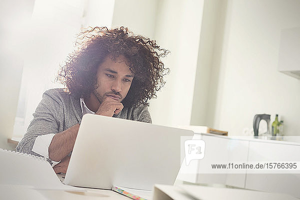 Konzentriert arbeitender junger Mann am Laptop