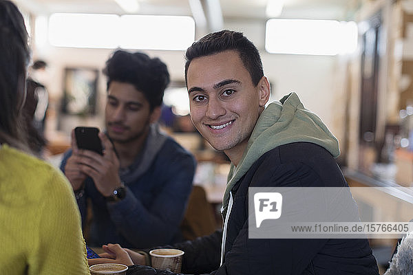 Porträt eines selbstbewussten jungen Mannes  der mit Freunden in einem Café abhängt