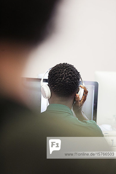 Reifer männlicher Community-College-Student mit Kopfhörern am Computer