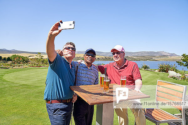 Männliche Freunde trinken Bier und machen ein Selfie auf der Terrasse des Golfplatzes