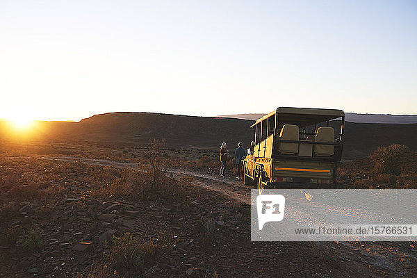 Safari-Geländewagen und Touristen bei Sonnenuntergang am Straßenrand Südafrikas