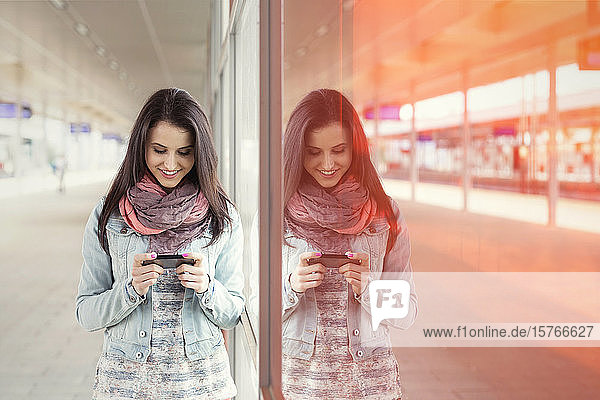 Junge Frau benutzt Smartphone im Bahnhof