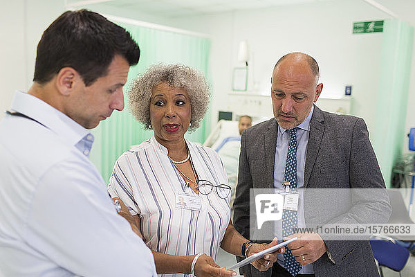 Doctors with digital tablet making rounds  consulting in hospital room