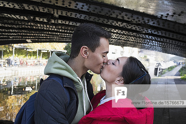 Zärtliches junges Paar  das sich unter einer Brücke küsst