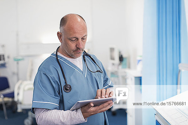 Männlicher Arzt mit digitalem Tablet im Krankenhauszimmer