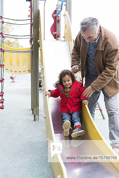 Großvater spielt mit Kleinkind Enkel auf Spielplatz Rutsche