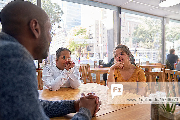 Mentorin und junge Frau mit Down-Syndrom im Gespräch im Café