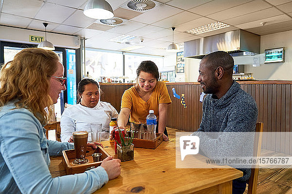 Junge Kellnerin mit Down-Syndrom serviert Getränke in einem Cafe