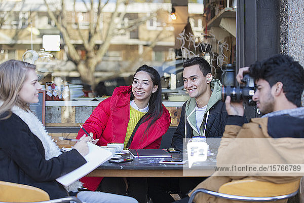 Junge Freunde hängen in einem Straßencafé ab und lernen
