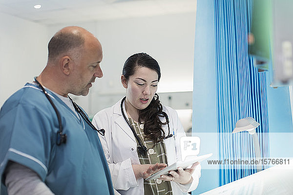 Ärzte mit digitalem Tablet im Gespräch im Krankenhauszimmer
