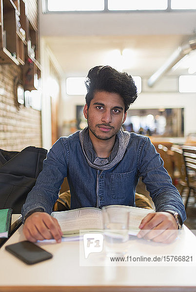 Porträt selbstbewusster junger männlicher Student  der am Cafétisch studiert