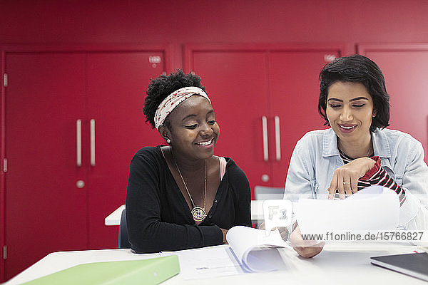 Studentinnen einer Volkshochschule diskutieren über Papierkram im Klassenzimmer