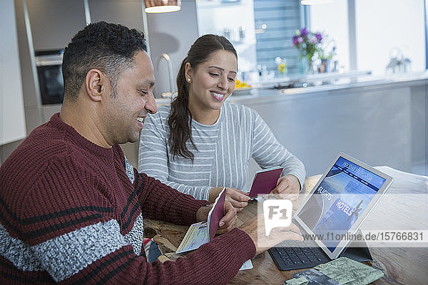 Glückliches Paar mit Pässen plant Urlaub am digitalen Tablet