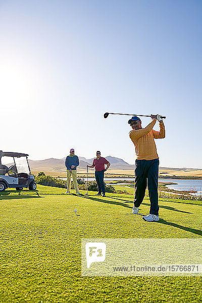 Männlicher Golfer beim Abschlag auf einem sonnigen Golfplatz