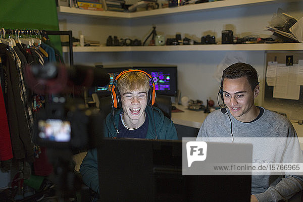 Glückliche Teenager mit Kopfhörern spielen Videospiele am Computer in einem dunklen Raum