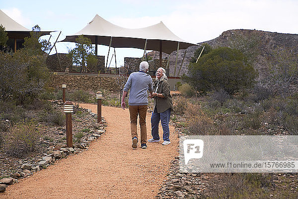 Happy senior couple walking on footpath outside safari lodge