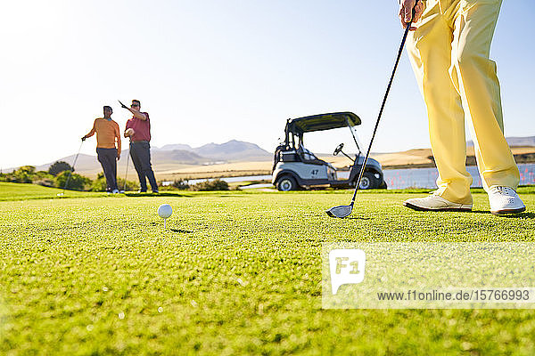 Golfer bereitet sich am sonnigen Abschlagplatz auf den Abschlag vor
