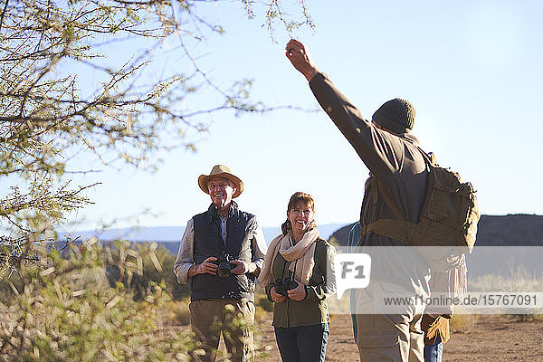 Safari-Führer erklärt einer Gruppe Bäume auf einer sonnigen Wiese