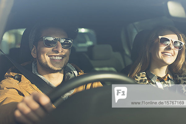 Glückliches junges Paar mit Sonnenbrille im Auto