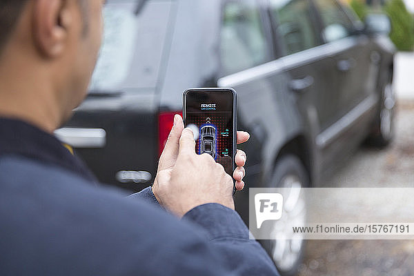 Mann stellt Autoalarm mit Smartphone in der Einfahrt ein