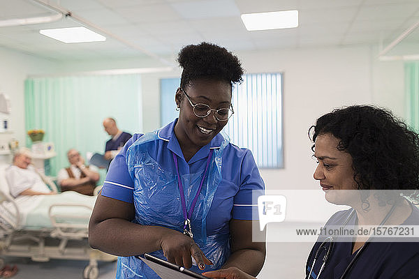 Female doctor and nurse with digital tablet making rounds  consulting in hospital room