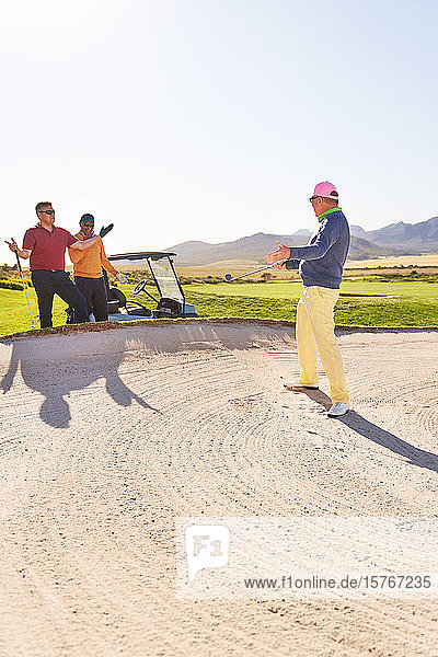 Männlicher Golfer im Bunker auf einem sonnigen Golfplatz