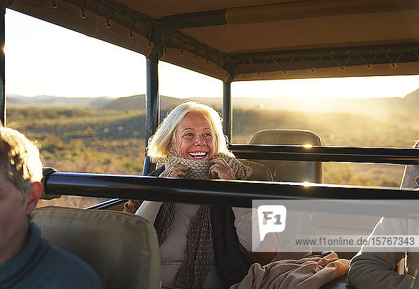 Happy senior woman on safari riding in off-road vehicle