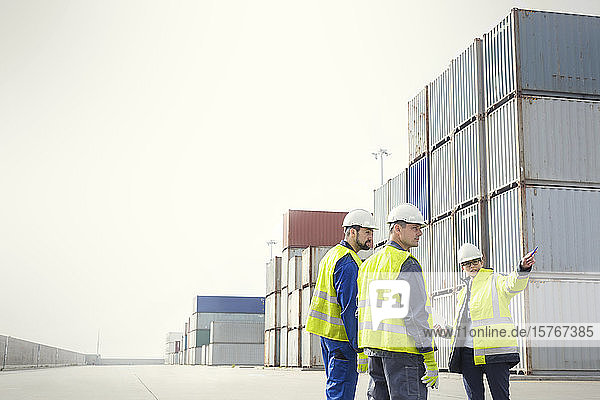 Dockarbeiter und Manager im Gespräch an Frachtcontainern auf einer Werft