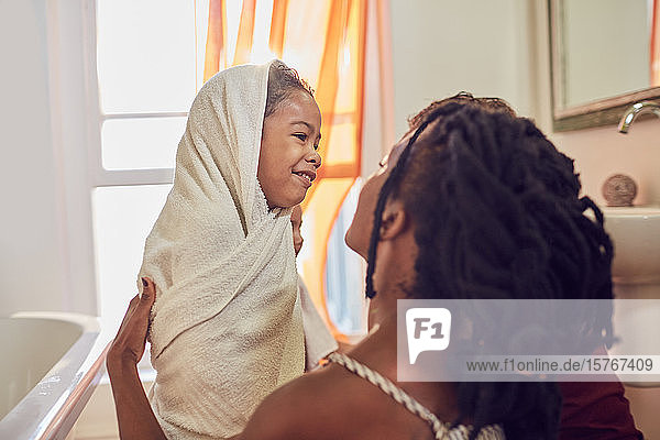 Glückliche Mutter trocknet ihre Tochter nach dem Bad mit einem Handtuch ab