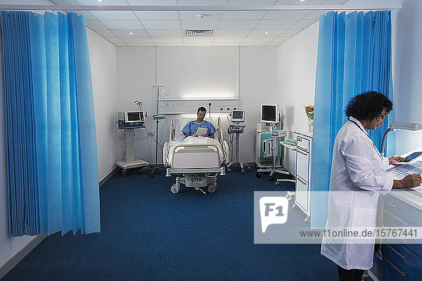 Male patient using digital tablet  resting in hospital bed